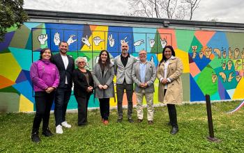Autoridades y funcionariado posan para la fotografía oficial, delante del mural de lengua de señas inaugurado