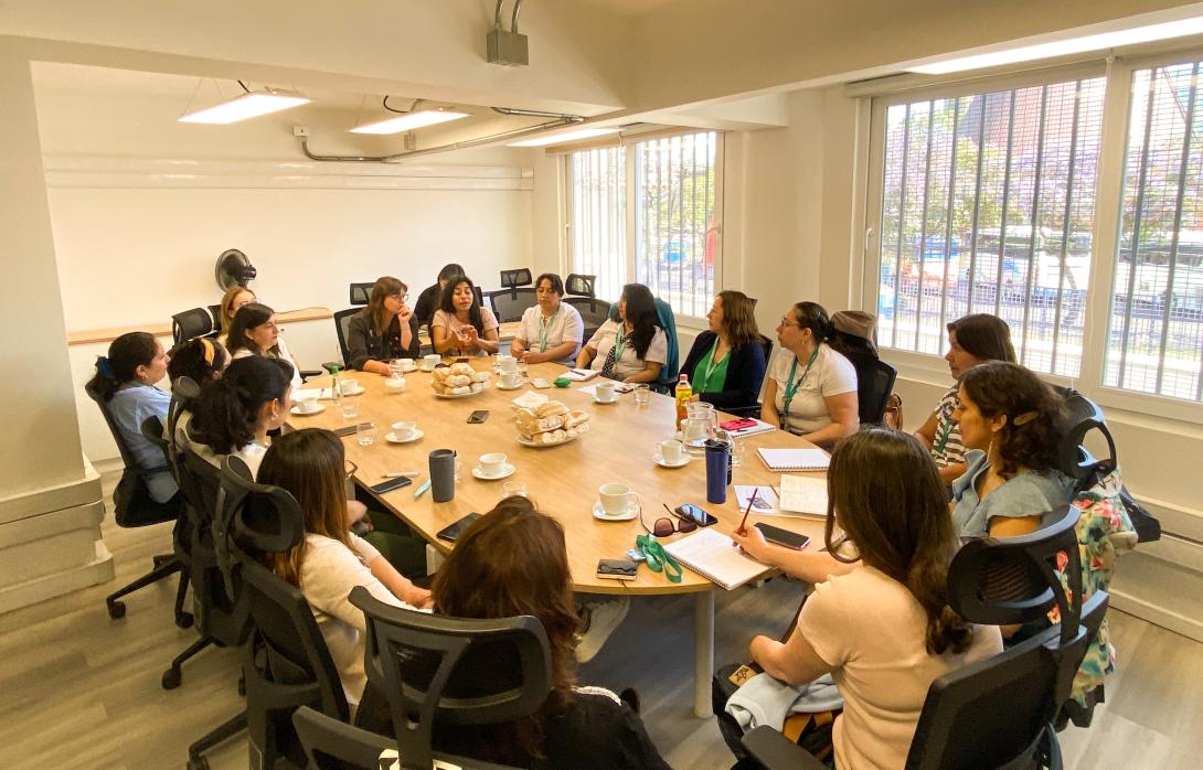 Mesa de reunión donde varias mujeres conversan acerca de los cuidados y sus desafíos