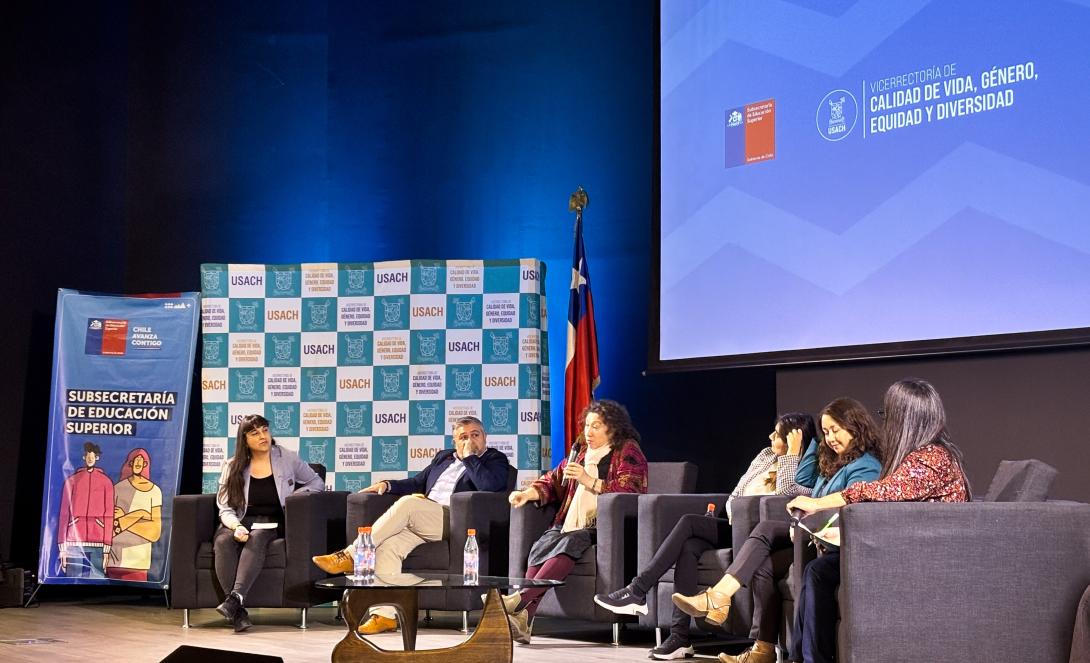Panelistas en el escenario del auditorio FAE. Al fondo se ve un pendón de la Subsecretaría de Educación Superior y otro de la Vicerrectoría de Calidad de Vida, Género, Equidad y Diversidad
