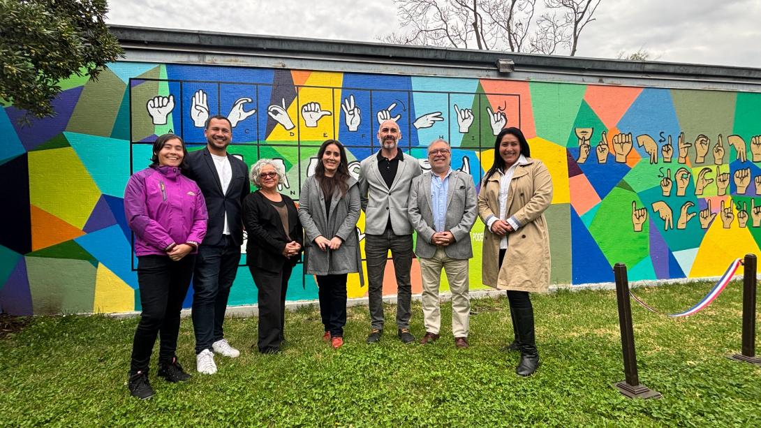 Autoridades y funcionariado posan para la fotografía oficial, delante del mural de lengua de señas inaugurado