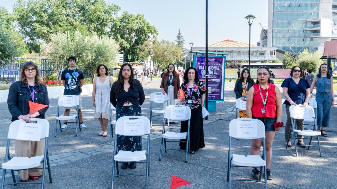 Representantes de las articulaciones de género de la Usach posan paradas al costado de unas sillas vacías que simbolizan a las víctimas de femicidio de este año